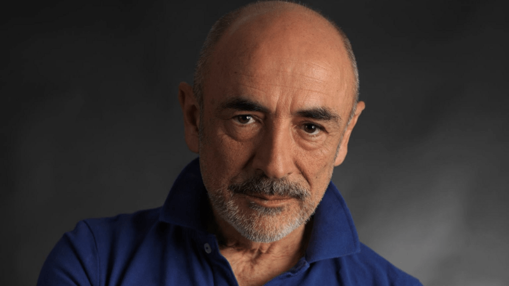 Pascal Lacrocq d'Iverness est un homme dans la soixantaine, avec des yeux noirs, presque chauve et une légère barbe poivre et sel, un tee-shirt bleu