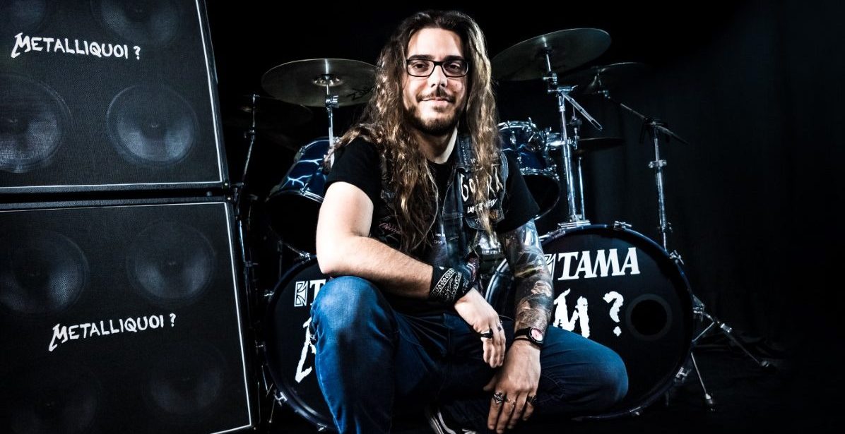 Hubert, alias le YouTuber Metalliquoi devant sa batterie, vêtu d'un jean et d'un tee-shirt noir.