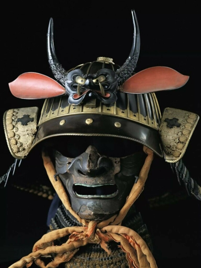 La photographie d'un casque de samurai, sur lequel est sculpté un petit démon amusant.