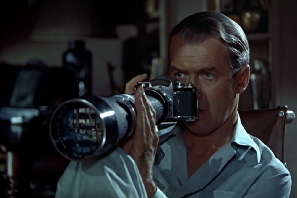 James Stewart, un appareil photo à la main, qui observe avec intérêt ses voisins.
