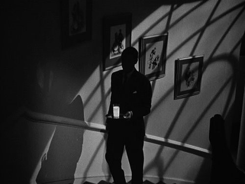Un homme monte lentement des escaliers dans le noir, et porte sur un plateau un verre de lait qui brille de manière suspecte... Serait-ce du poison ??