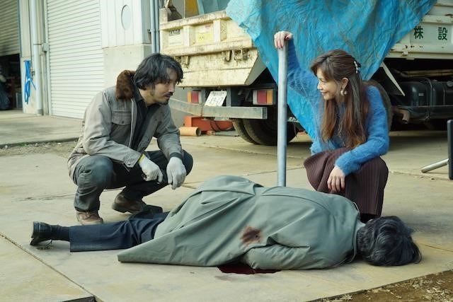 Mme Tanabe est en train de sourire, en proposant d'enterrer Saito ! Elle tient une barre de fer, dont elle s'est servi pour l'assommer, quelques instants plus tôt !