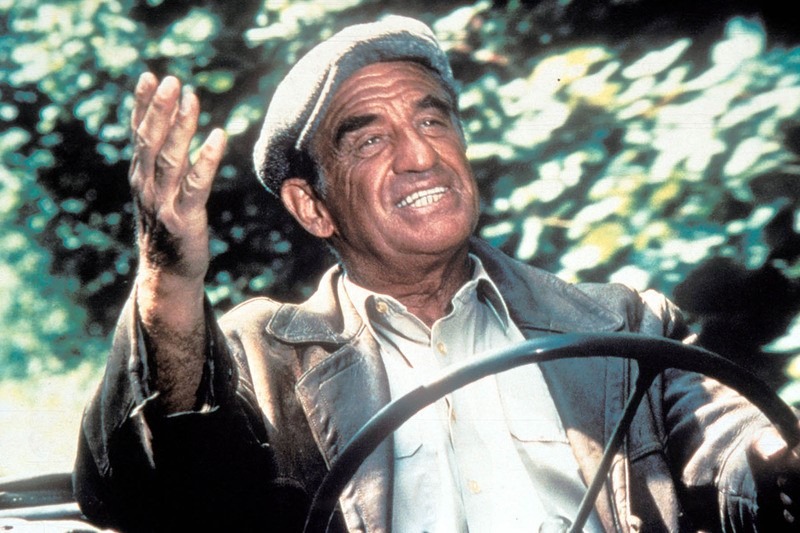 Belmondo avec un béret, au volant d'une voiture.