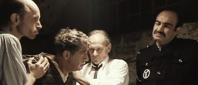 Le policier en train d'ordonner qu'on mette la tête sous l'eau au héros, Henri Fortin, qui est prisonnier.