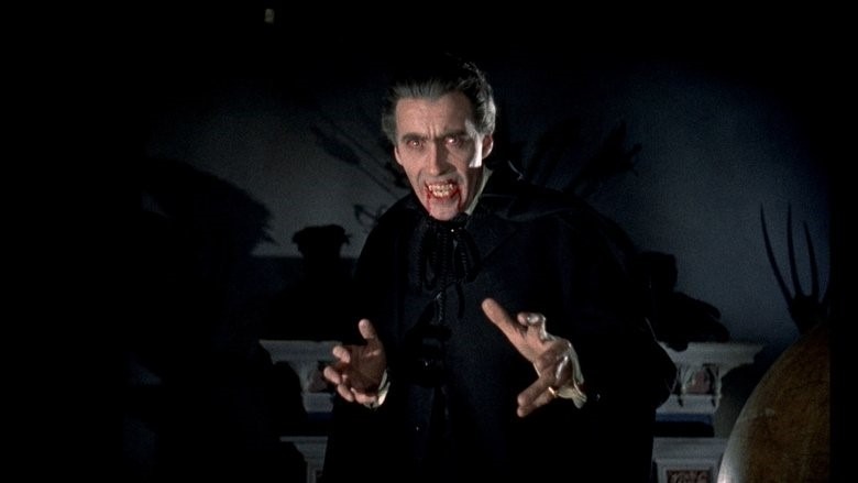 Avec sa silhouette longue et mince, ses cheveux gris bien coiffés et son habit noir, Christopher Lee a vraiment le type du vampire aristocrate. Sur l'image, il a les canines sorties et les yeux luisants.