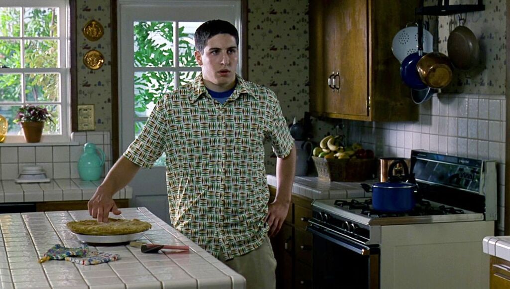 Photo montrant Jim (Jason Biggs) dans sa cuisine, deux doigts insérés dans le centre d'une tarte aux pommes tiède. Sa chemise est vraiment moche, et sa coupe de cheveux est douteuse.
