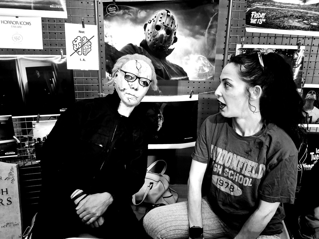 Ils sont deux. Un des deux porte un masque de tueur en série avec des lunettes par-dessus, et l'autre, le regarde, l'air béat.