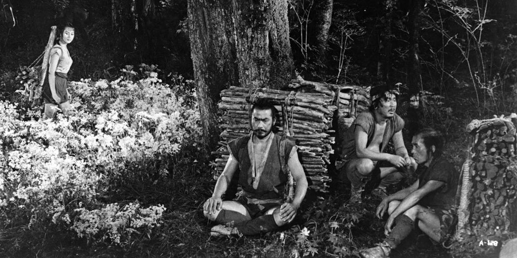 Scène du film La Forteresse cachée d’Akira Kurosawa montrant le général Rokurōta et deux paysans dans une forêt, avec la princesse Yuki en arrière-plan