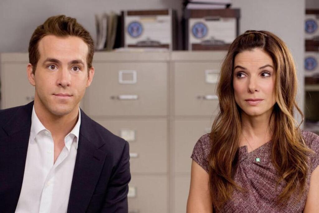 Photographie du film La Proposition (The Proposal), réalisé par Anne Fletcher en 2009, montrant Sandra Bullock et Ryan Reynolds assis côte à côte dans un bureau.